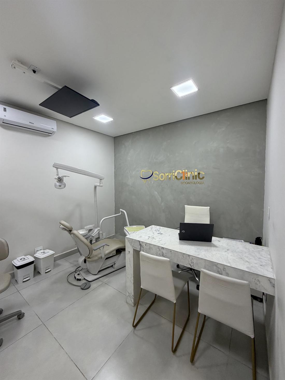 Consultório da SorriClinic com cadeira odontológica e logotipo na parede